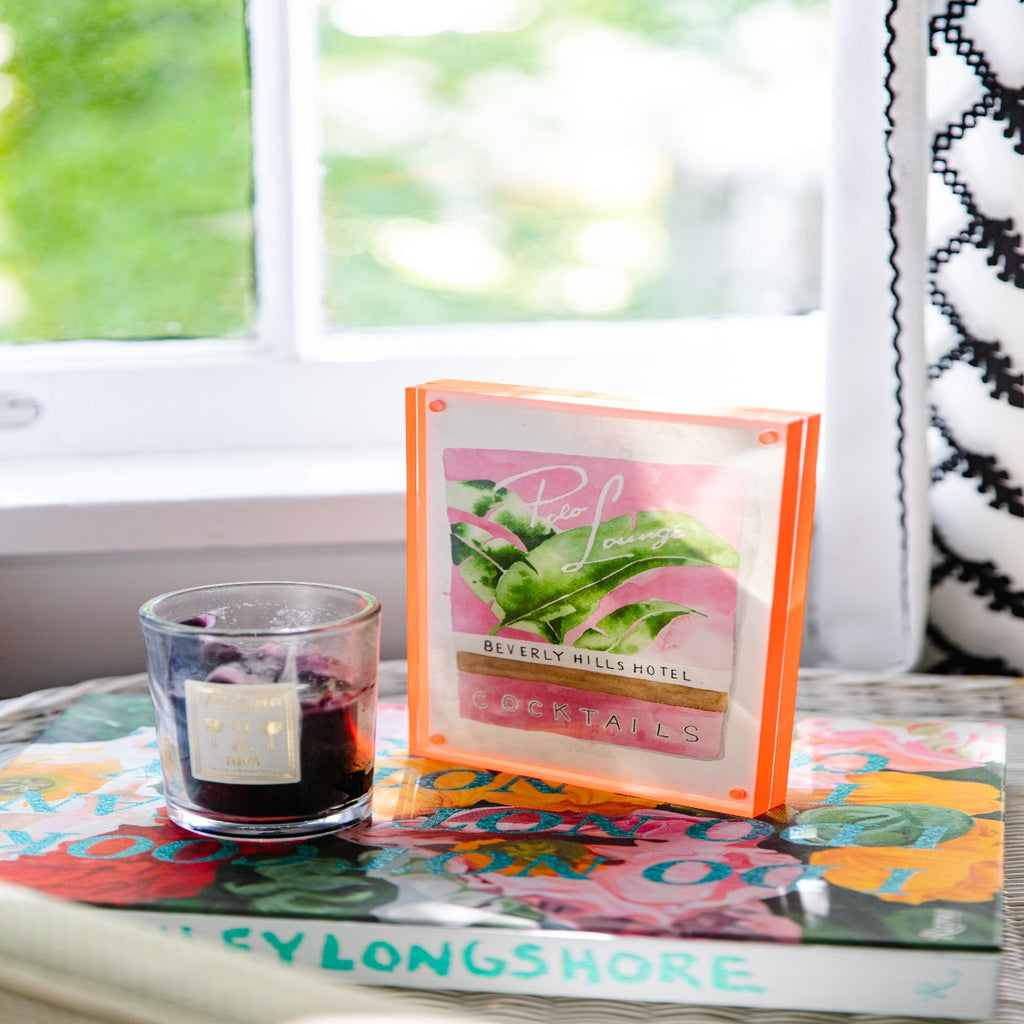 Beverly Hills Matchbook - Furbish Studio, Beverly Hills Hotel Photo Lounge matchbook watercolor print featuring a collection of Banana leaves with a pink background enclosed in a 5" x 7" orange magnetic acrylic floating frame