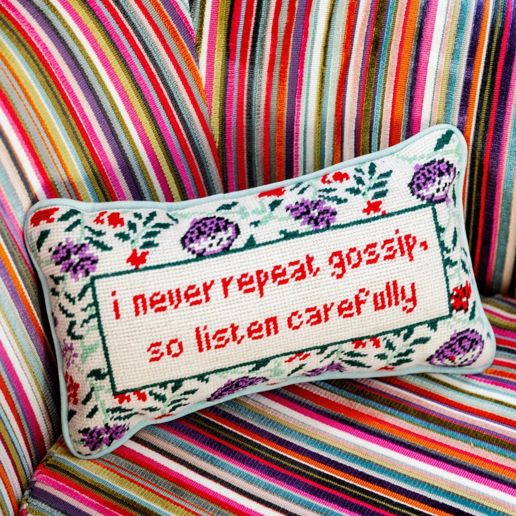 a closer look of a hand embroidered in wool and backed in luxe mint green velvet chic needlepoint pillow with "I never repeat gossip, so listen carefully" cheeky saying in front sitting on a colorful couch