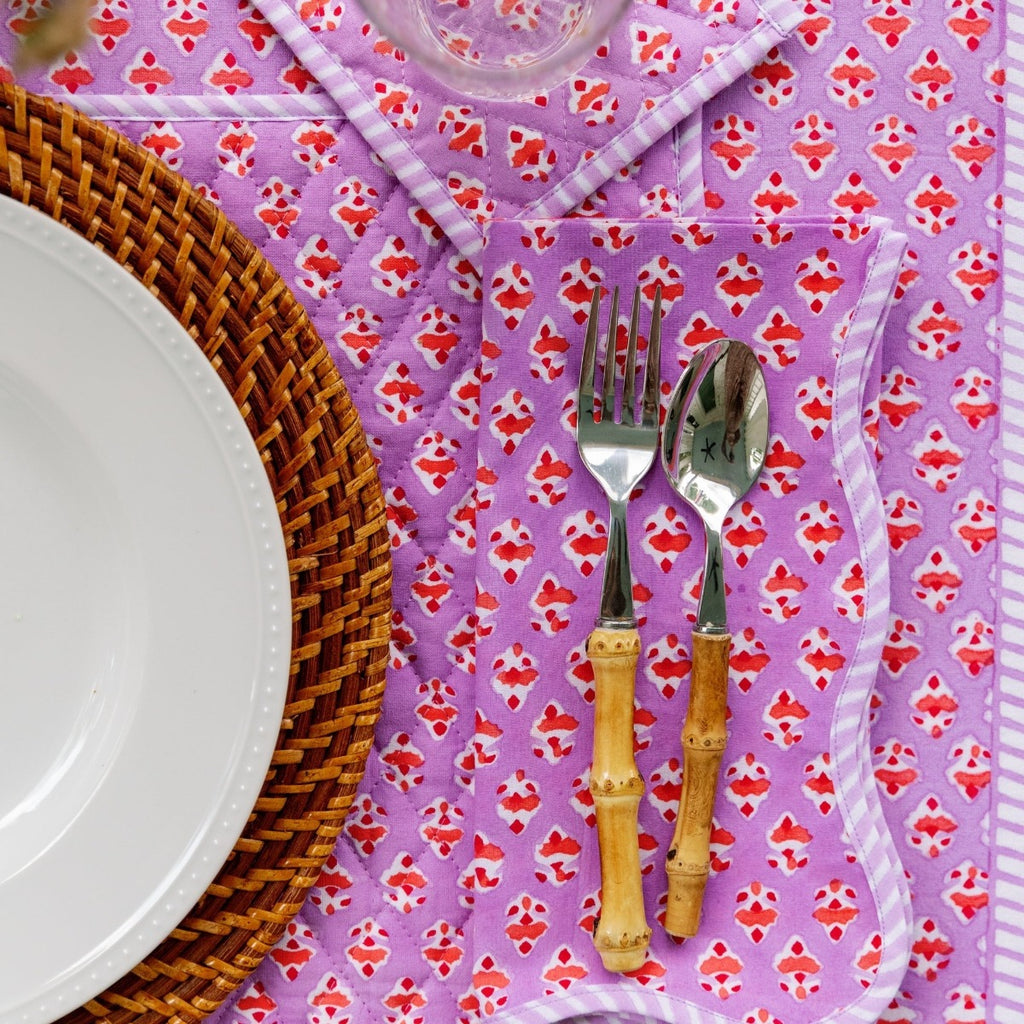 a beautiful table setting showcasing Ambroeus table linens with a spoon and fork positioned to the right of the plate, a glass above the silverware and a table cloth beneath all of them
