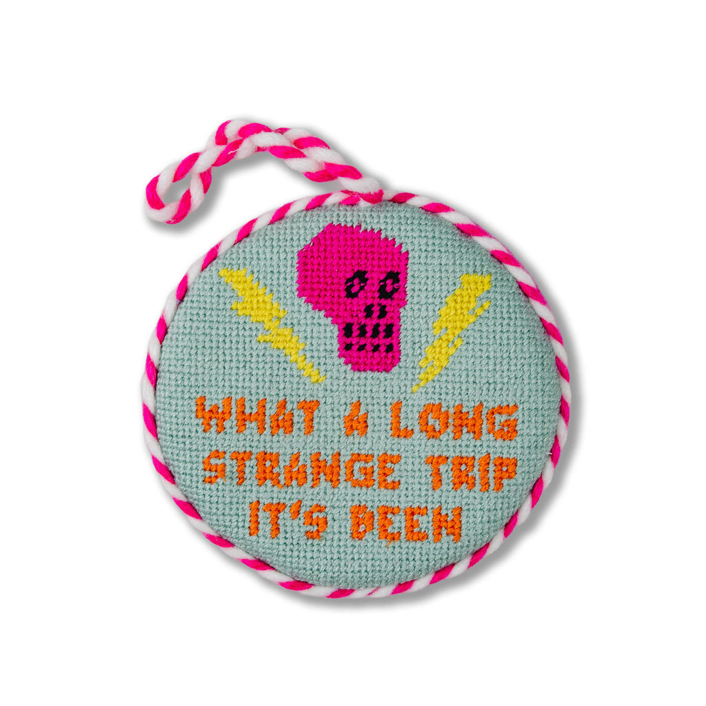 Round embroidered item with a pink skull design and text on a white background