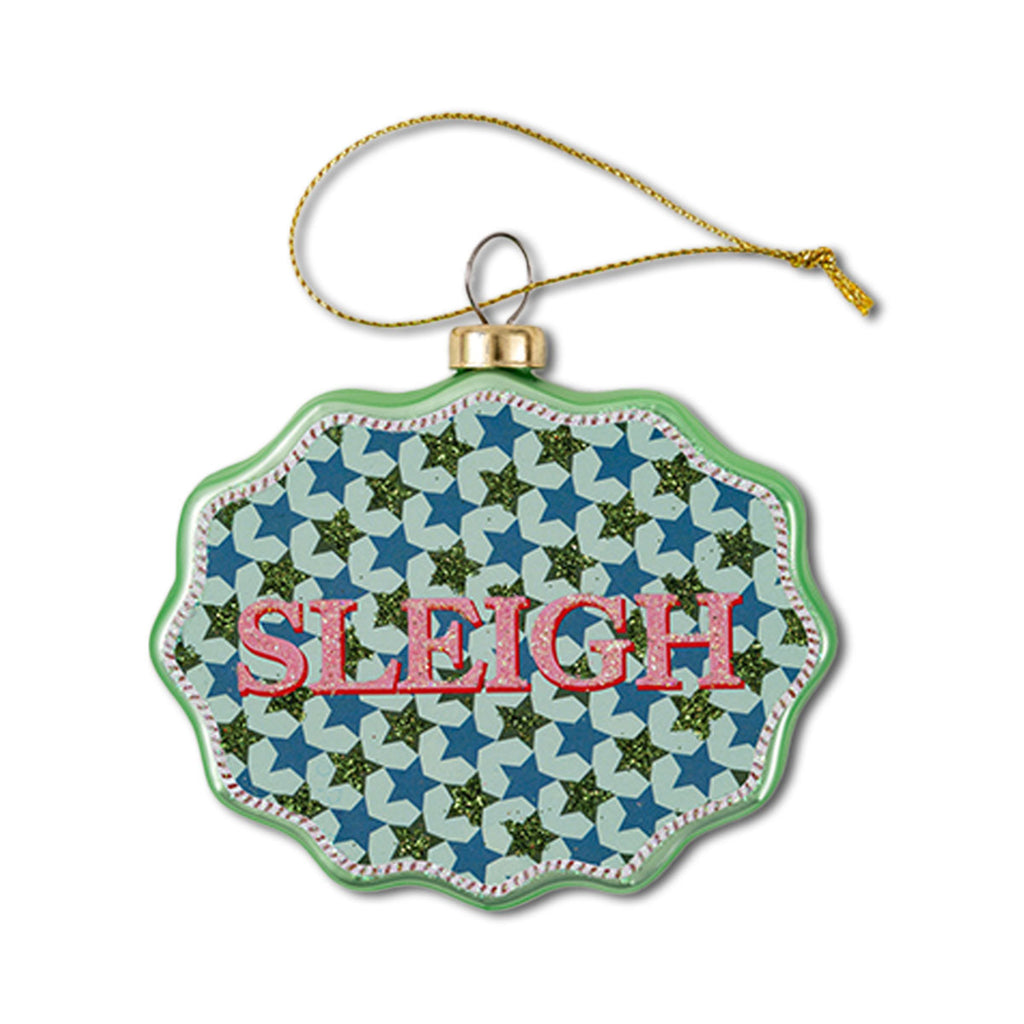 A scalloped glass ornament with a green border and a pattern inside featuring the word 'SLEIGH' in red letters, with a blue background and star patterns.