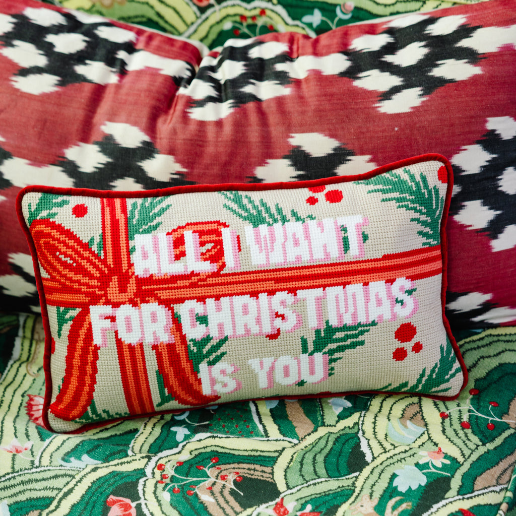 Decorative pillow with Christmas message on a patterned fabric background