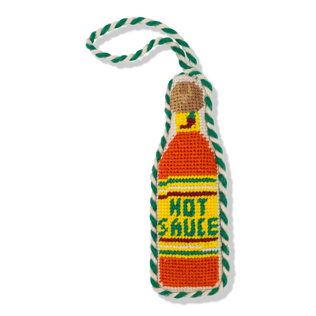 Knitted hot sauce bottle toy with a rope handle on a white background