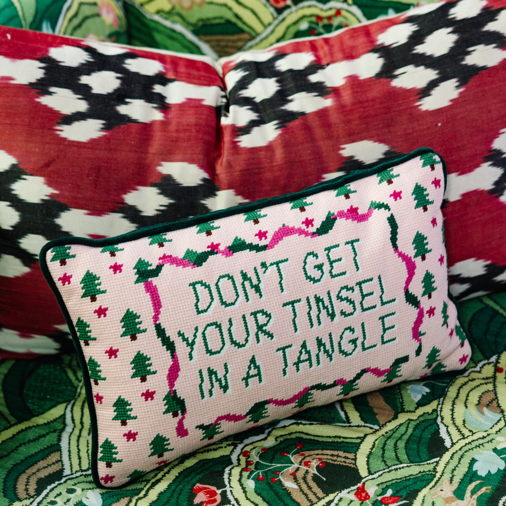 Decorative pillow with Christmas-themed text on a patterned couch