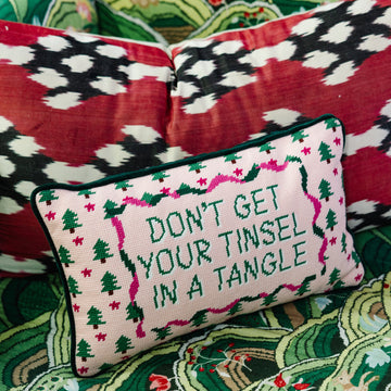 Decorative pillow with Christmas-themed text on a patterned couch