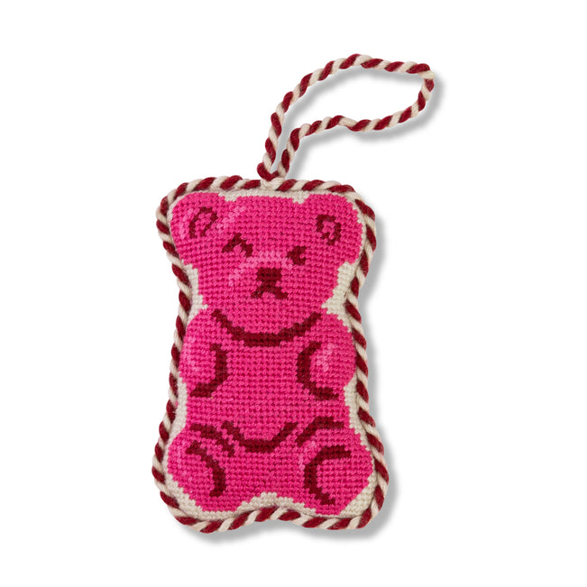 Pink bear-shaped knitted toy with red and white rope on a white background