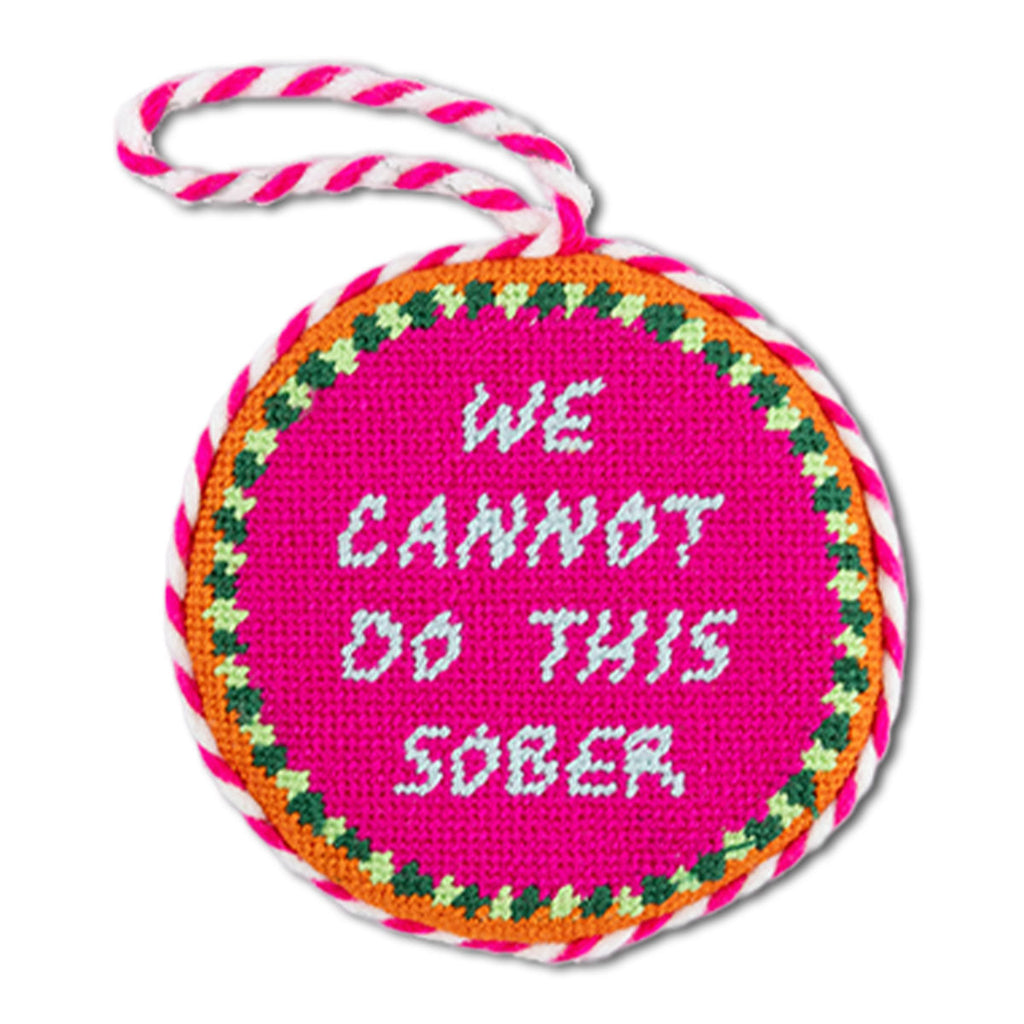 Circular pink sign with 'WE CANNOT DO THIS SOBER' text, surrounded by colorful border and string handle.