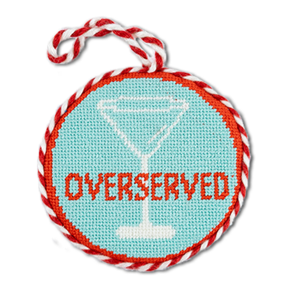 Round needlepoint ornament with 'Overserved' text and martini glass design, wrapped in red and white string.