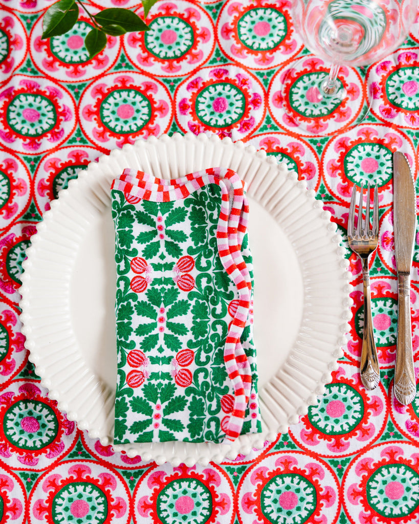 Decorative table setting with a colorful patterned tablecloth, white plates, and a green and red napkin.