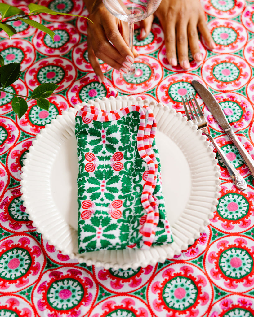 Patterned tablecloth with a place setting including a napkin, plate, and cutlery.