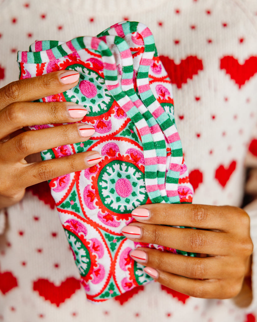 Colorful patterned fabric held by a person against a heart-patterned background