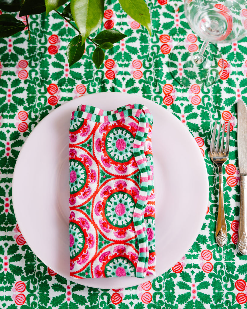 Table setting with a colorful napkin, plate, and cutlery on a patterned tablecloth.