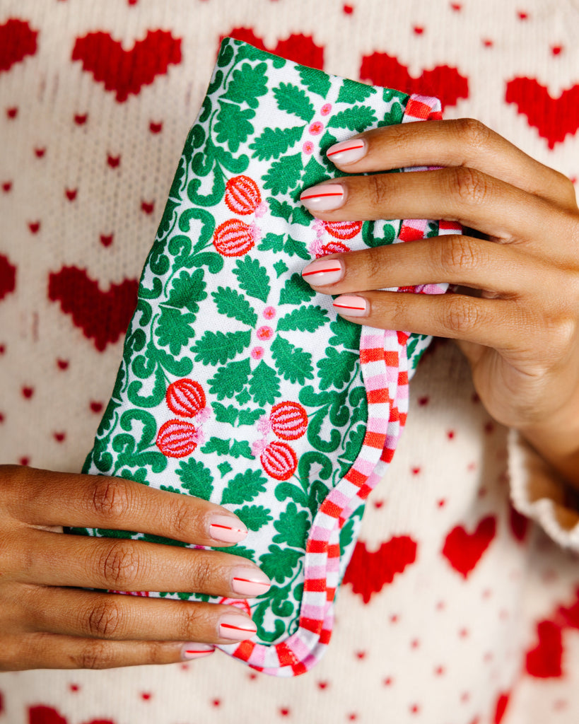 Hand holding a patterned fabric against a heart-themed background