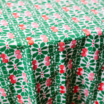 Close-up view of a round tablecloth with a green base and red pomegranate patterns.