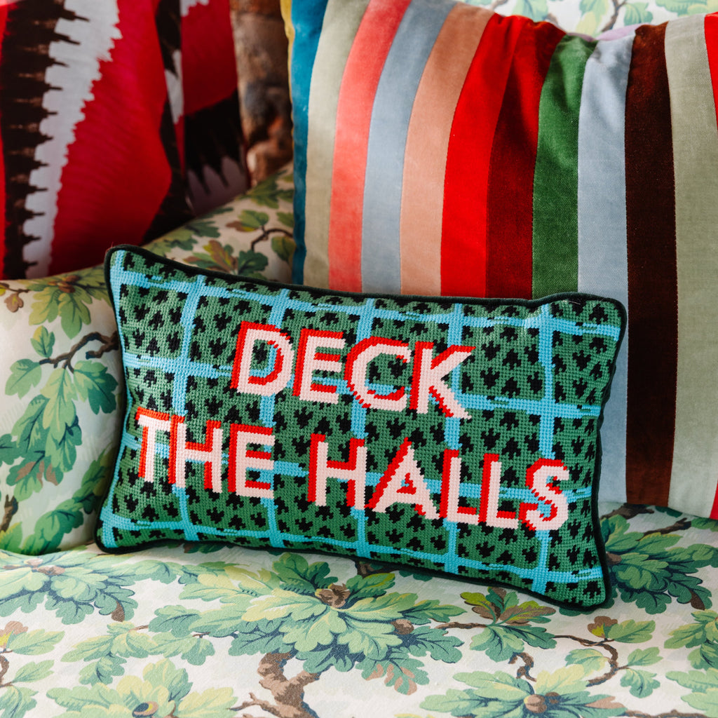 Decorative pillow with 'DECK THE HALLS' text on a floral-patterned chair.