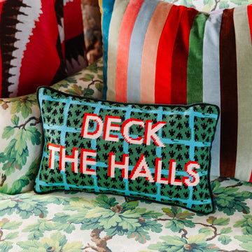 Decorative pillow with 'DECK THE HALLS' text on a floral-patterned chair.