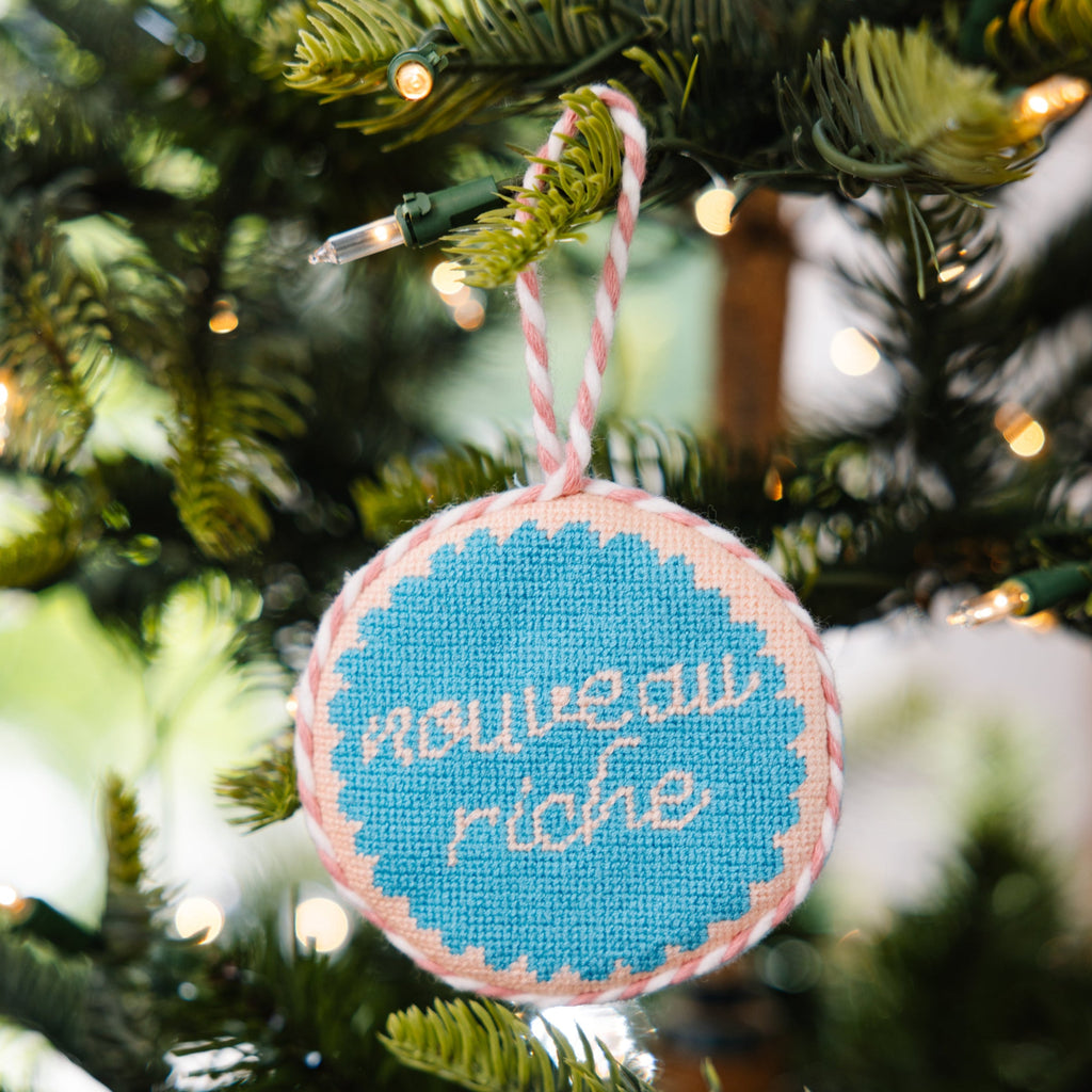 Decorative ornament with 'nouveau riche' text on a Christmas tree.