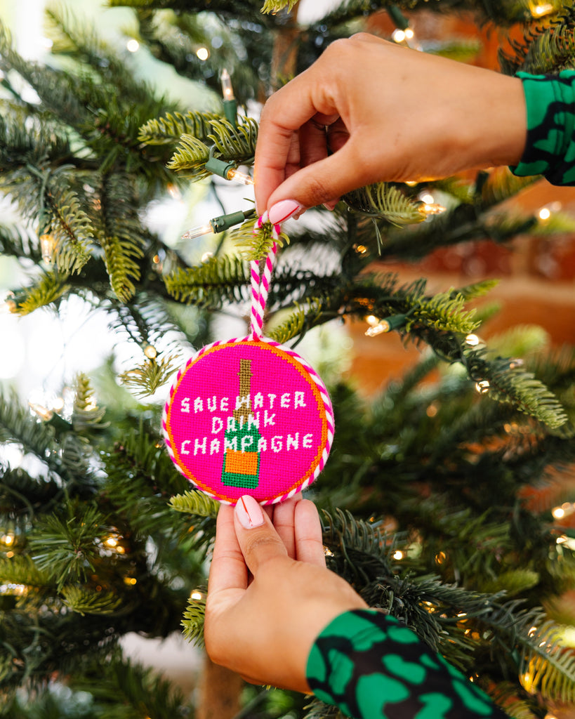 Person hanging a Christmas ornament with text on a decorated tree