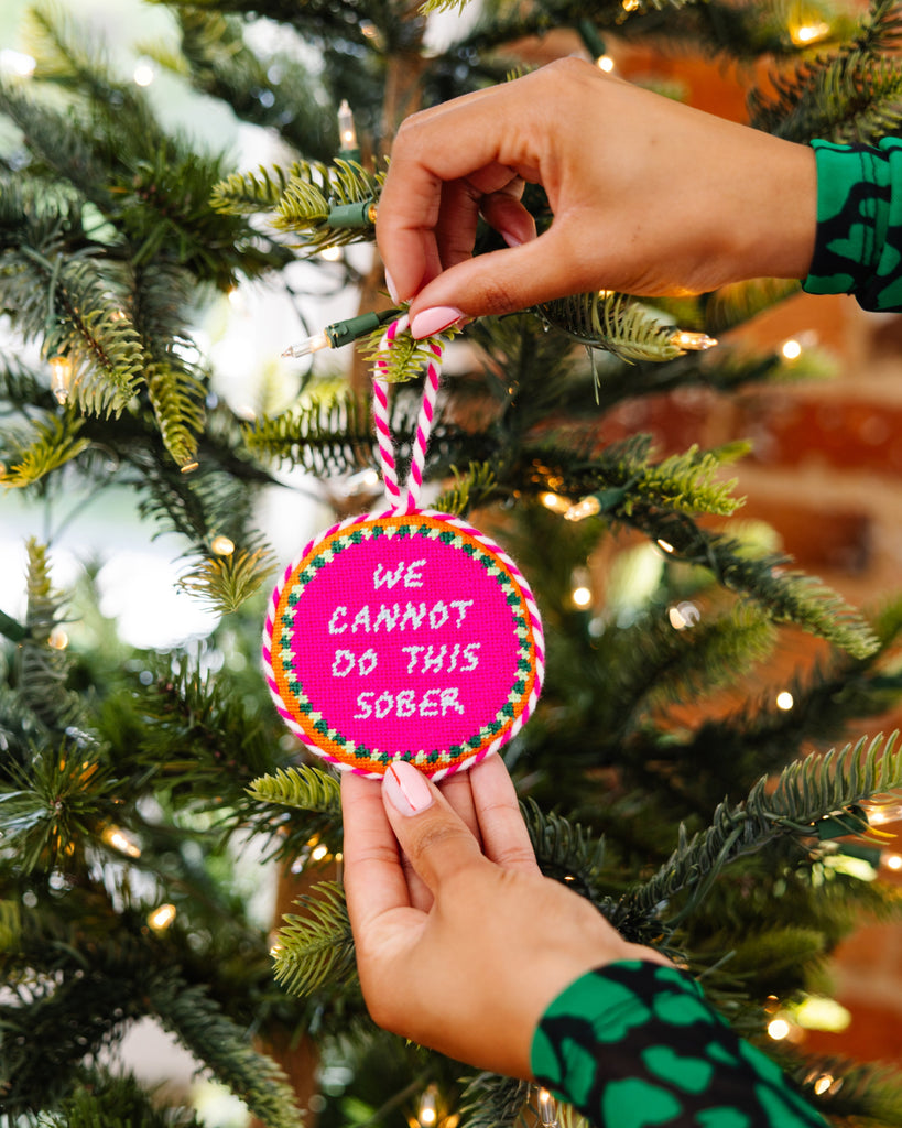 Person hanging a pink ornament with text on a Christmas tree