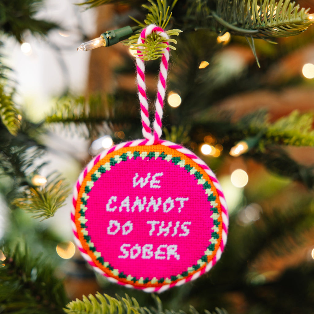 Decorative ornament with 'We cannot do this sober' text on a Christmas tree.