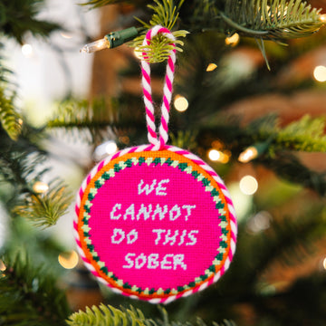 Decorative ornament with 'We cannot do this sober' text on a Christmas tree.