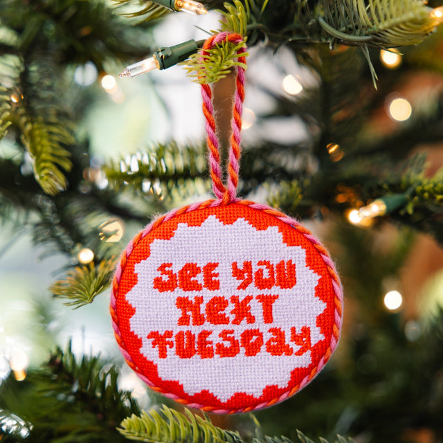 Decorative Christmas ornament with 'See you next Tuesday' text on a tree.