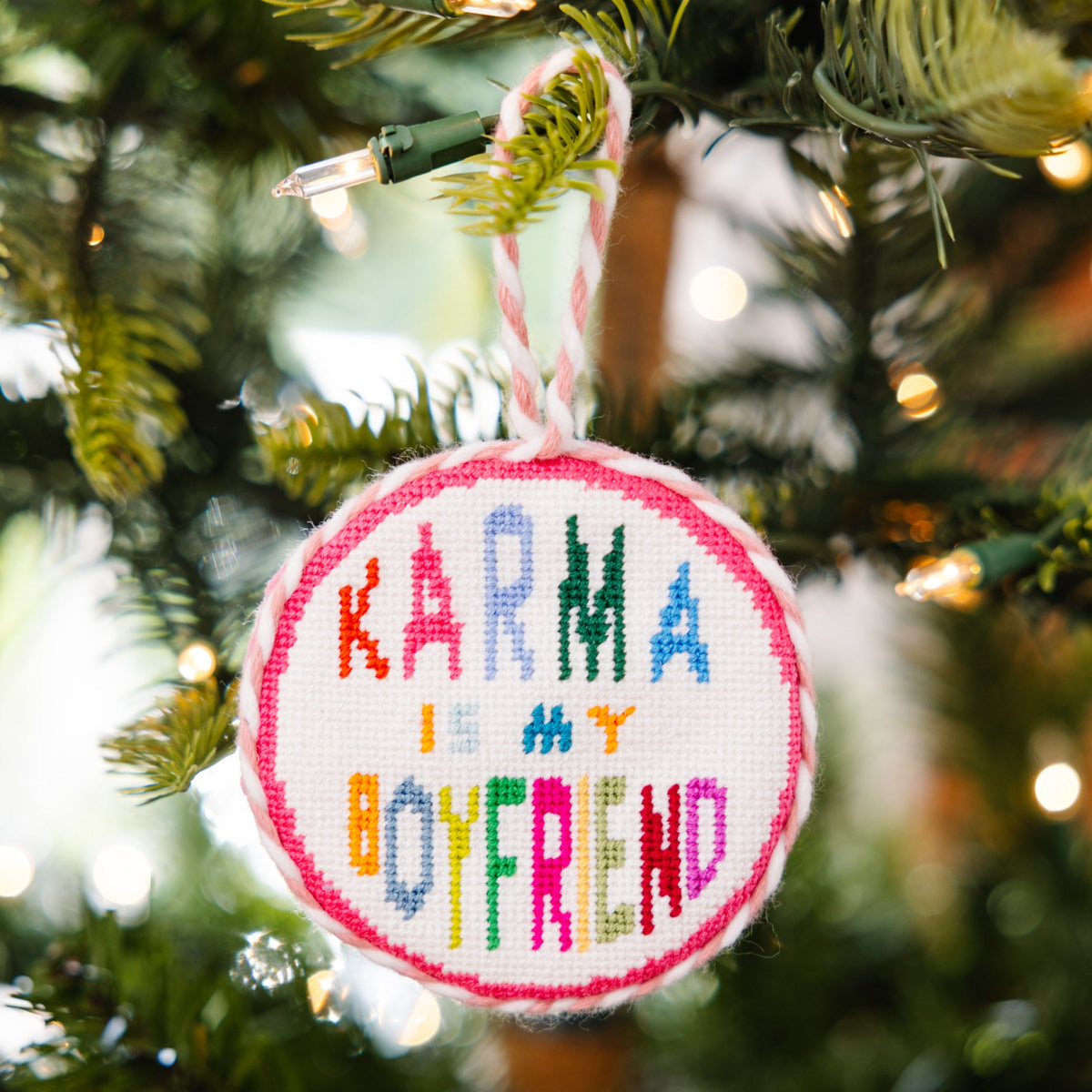 Decorative ornament with 'Karma is my boyfriend' text on a Christmas tree.