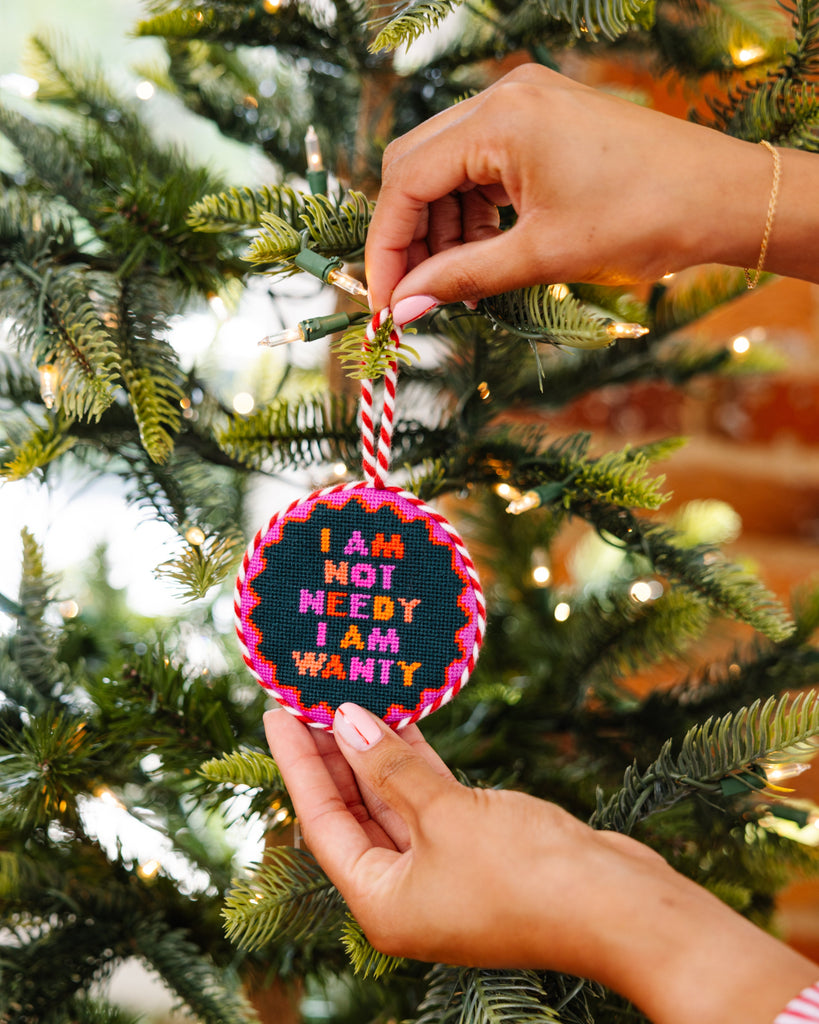 Hand holding a Christmas ornament with text on a decorated tree