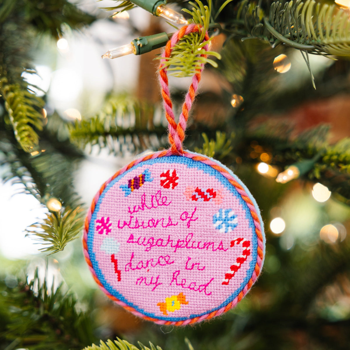 Decorative Christmas ornament with embroidered text on a tree