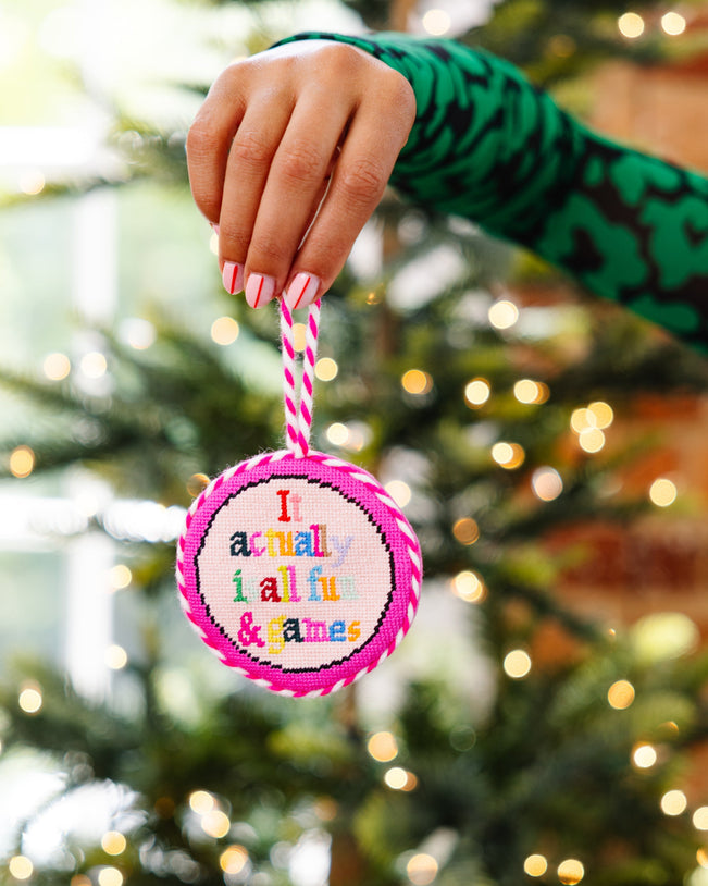 Hand holding a Christmas ornament with text in front of a decorated tree