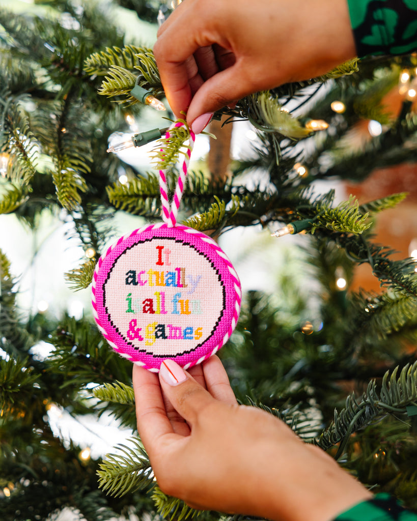 Person holding a colorful ornament with text on a Christmas tree