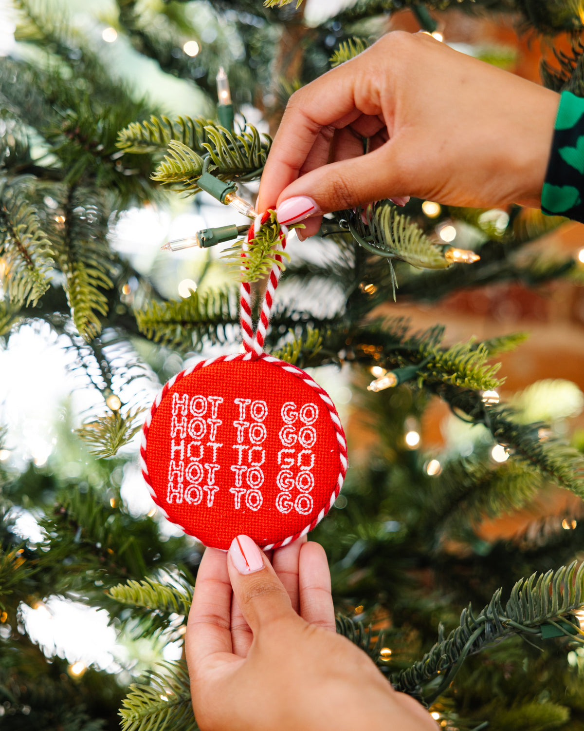 Red ornament with text being hung on a Christmas tree