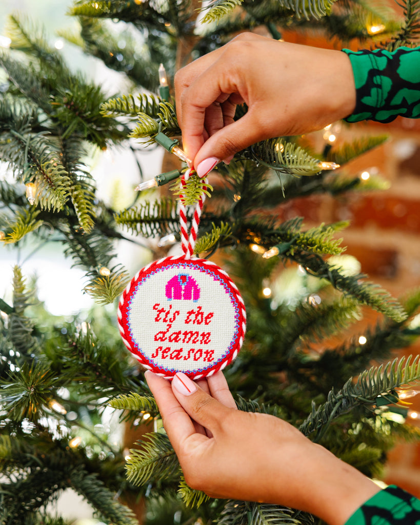 Person hanging a Christmas ornament with text on a decorated tree