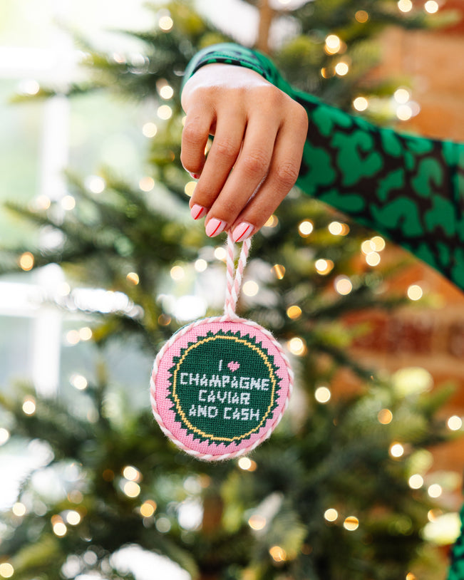 Hand holding a Christmas ornament with text in front of a decorated tree