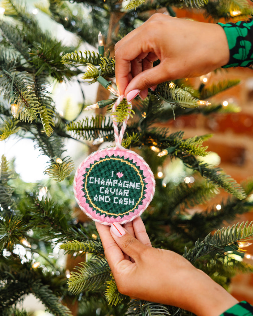 Hand holding a Christmas ornament with text on a decorated tree