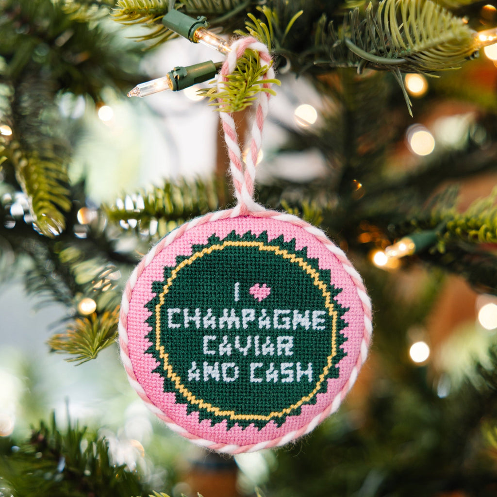 Decorative ornament with 'I love Champagne, caviar and cash' text on a Christmas tree.