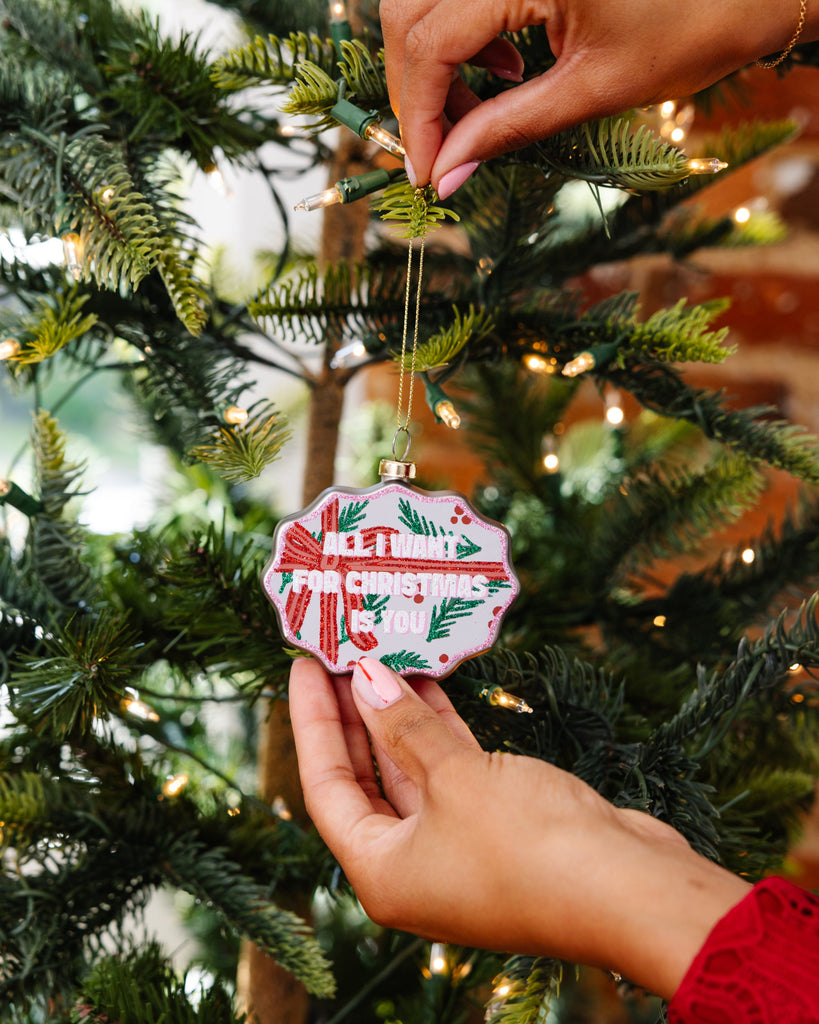 Person decorating a Christmas tree with a festive ornament.