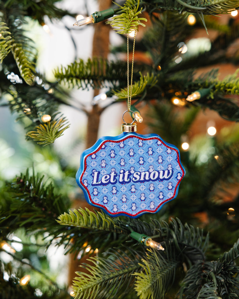 Decorative ornament with 'Let it snow' text on a Christmas tree.