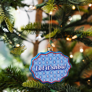 Decorative ornament with 'Let it snow' text on a Christmas tree.