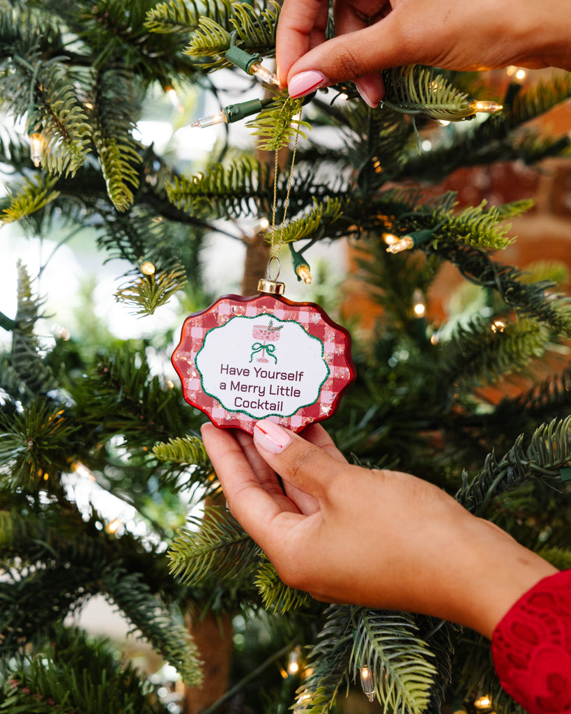 Person holding a Christmas ornament with text against a decorated tree background