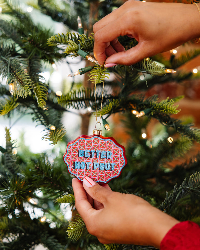 Person hanging a decorative ornament with text on a Christmas tree