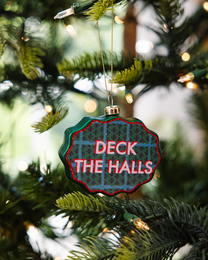 Decorative ornament with 'Deck the Halls' text on a Christmas tree.
