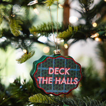 Decorative ornament with 'Deck the Halls' text on a Christmas tree.