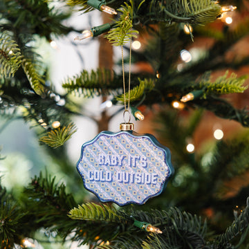 Decorative ornament with 'Baby it's cold outside' text on a Christmas tree.