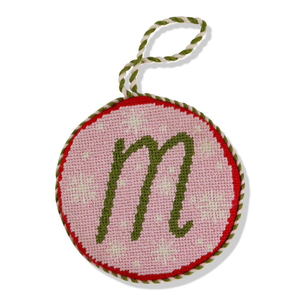 Round needlepoint ornament with letter 'm' on a white background
