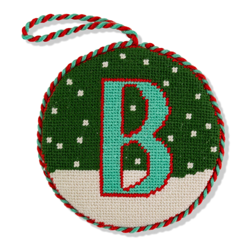 Round green ornament with letter 'B' on a white background