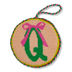 Circular needlepoint ornament with pink bow and green letter 'Q' on beige background