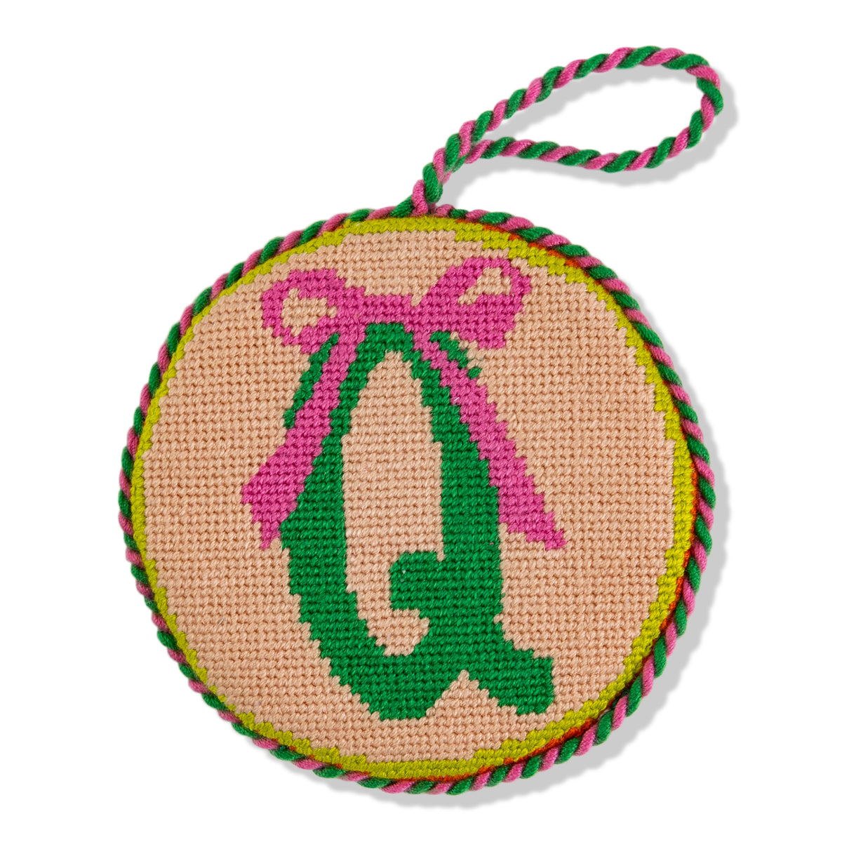 Circular needlepoint ornament with pink bow and green letter 'Q' on beige background