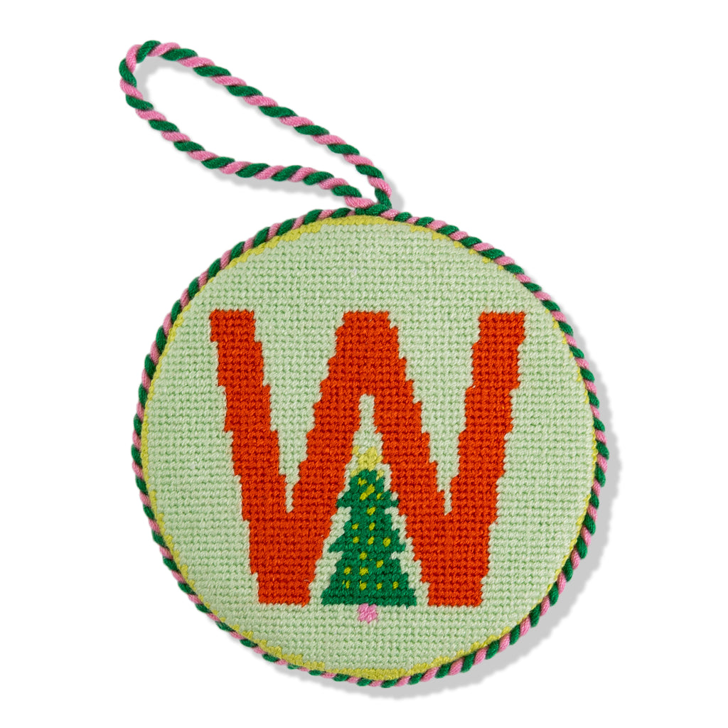 Circular needlepoint ornament with letter 'W' and Christmas tree design on a light green background.