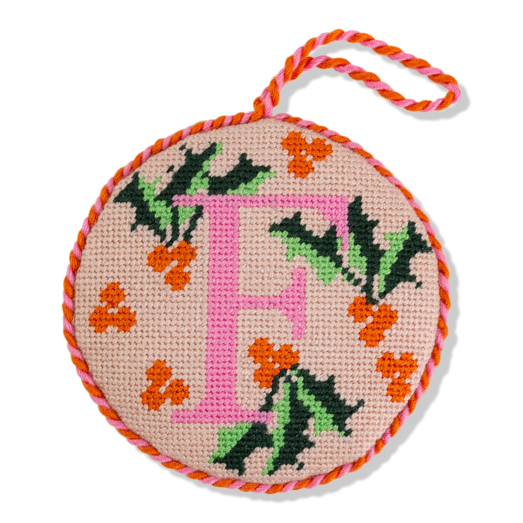 Circular needlepoint ornament with letter 'H' and floral patterns on a beige background.